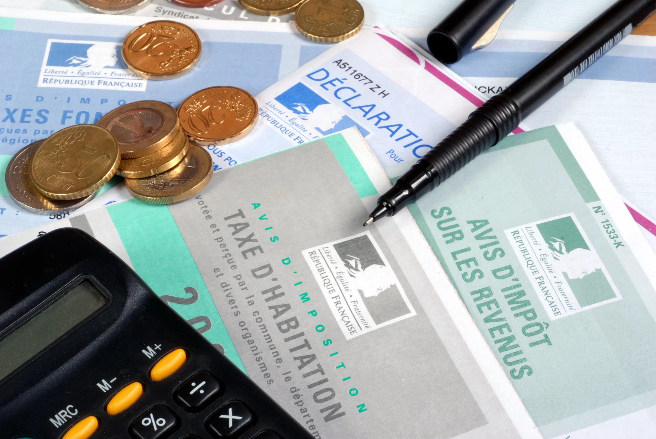 Photo représentant des pièces, une calculatrice et des feuilles d'impositions pour illustrer l'infoprenariat : Savais-tu que tes frais de formation peuvent réduire ton imposition ?